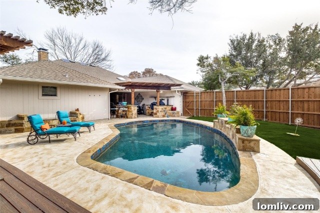 A picturesque view of the pool with its elegant water feature, surrounded by ample decking and lush greenery.