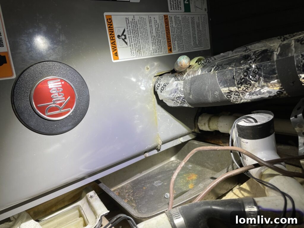 A baking pan incorrectly used as an HVAC condensate drain pan, showing stains from overflow.