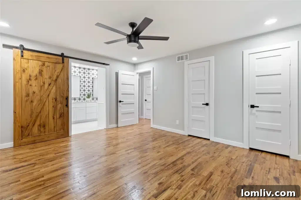 Stylish primary bathroom with double vanities, custom wood cabinets, large walk-in shower with designer tiles, and a wide mirror.