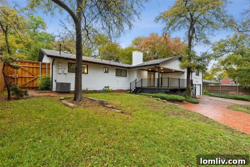 Exterior view of the Midcentury Modern home from the backyard, showcasing its renovated patio, lush lawn, and mature trees.