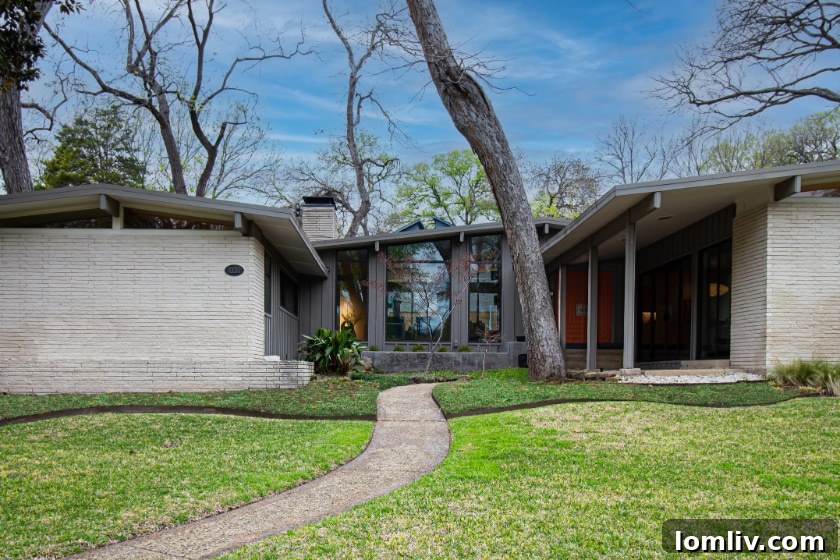 A stunning Midcentury Modern home exterior, featuring an orange front door and large windows amidst lush landscaping.