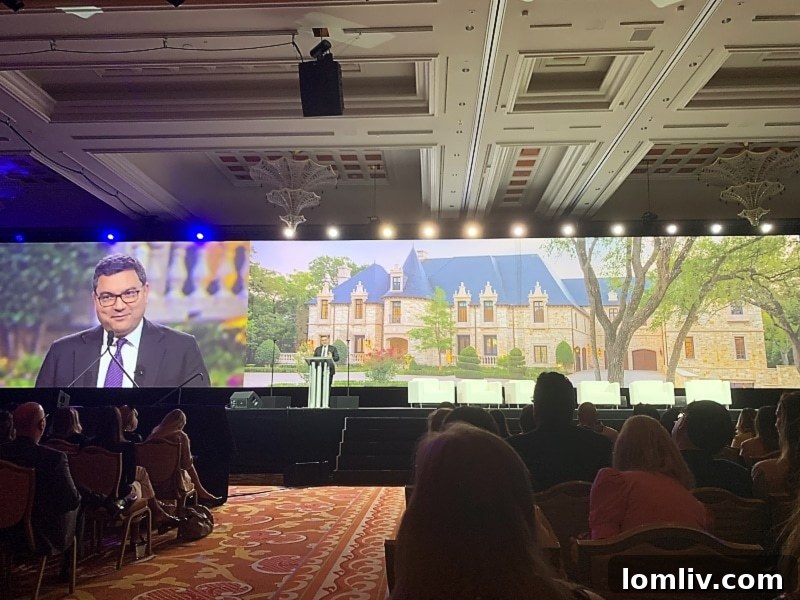 Mickey Alam Kahn, President of LPI, speaking with Ebby Halliday sale backdrop