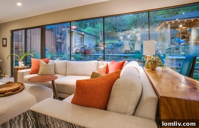 Living room with a wall of windows overlooking a luxurious backyard