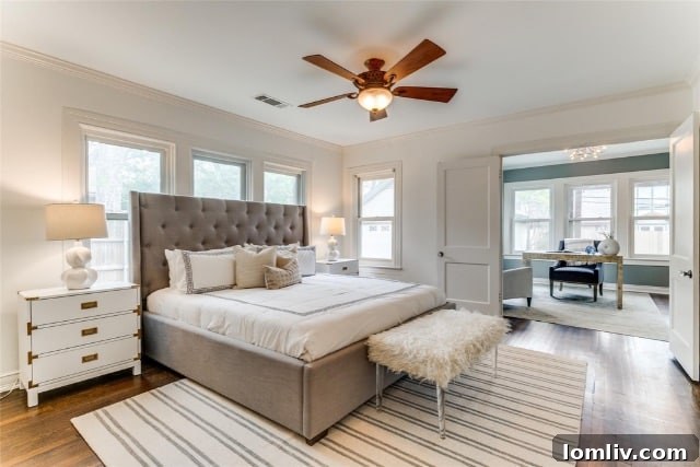 Spacious primary bedroom with gleaming hardwood floors and elegant designer lighting