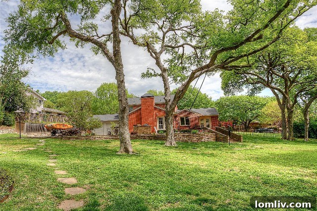 View of the stately Colonial home from the tranquil swimming pool, highlighting the expansive backyard and the dense canopy of mature trees providing ultimate privacy.