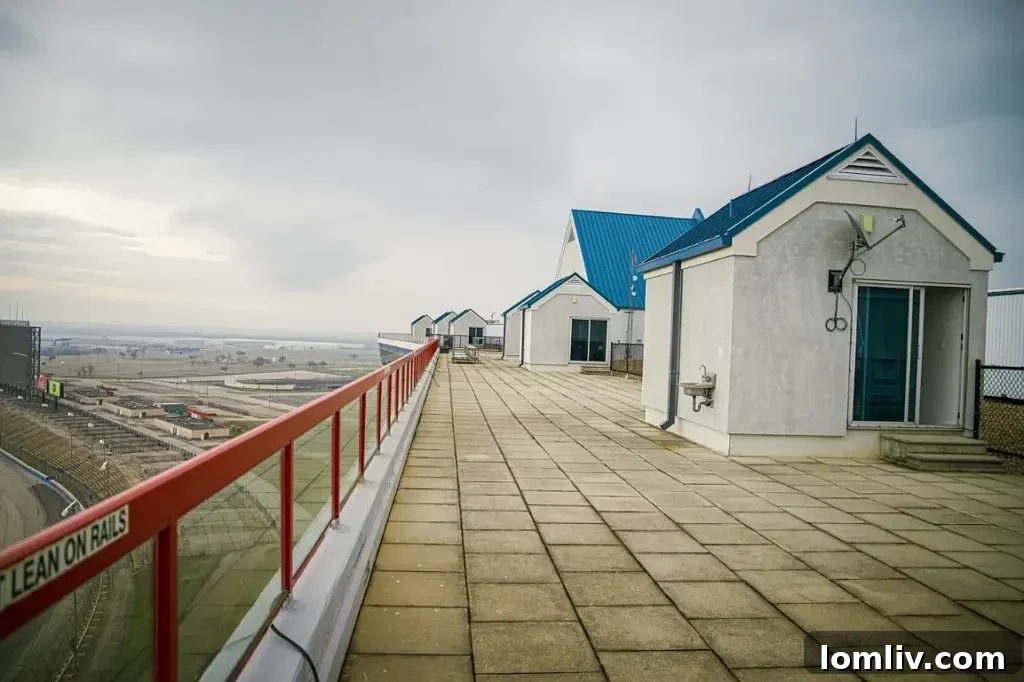 A.J. Foyt's Texas Motor Speedway Penthouse Accelerates Your Life 7 A spacious rooftop terrace with comfortable seating, offering panoramic views of a race track and surrounding landscape.