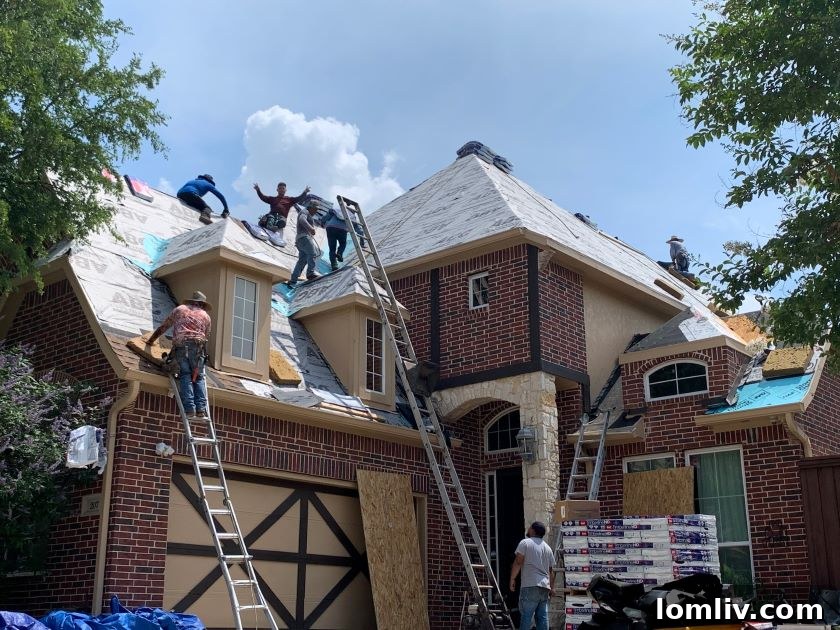 Roofers actively replacing a roof on a residential home after hail damage.