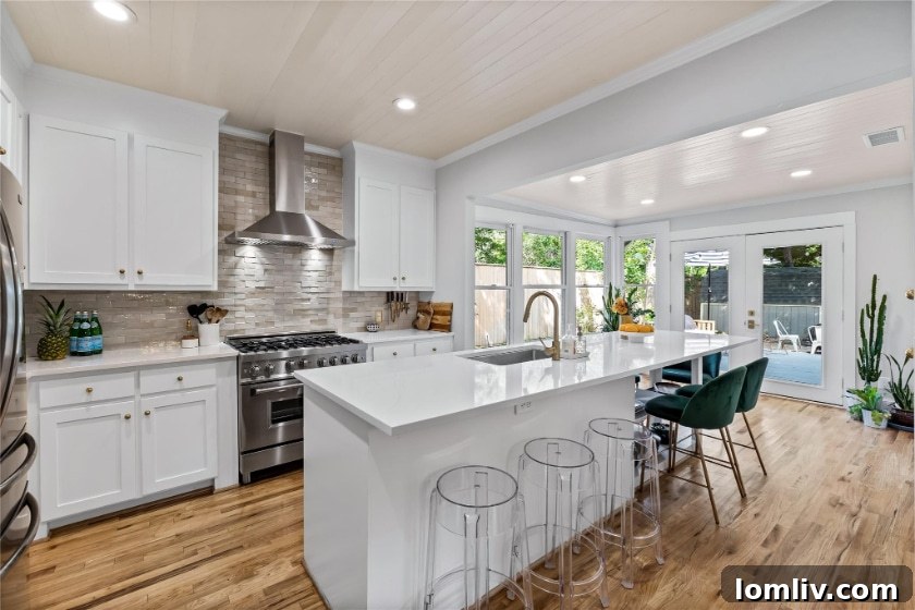 A wide shot of the modern kitchen with its large quartz island, custom shelving, and Zellige tile backsplash.