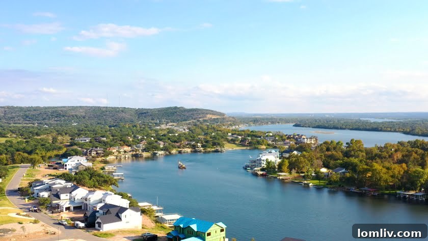 Scenic view of a tranquil lake with a modern lake house nestled on its shores, reflecting the calm water. Lush green trees line the background under a clear sky, symbolizing the peaceful escape of lakefront living.