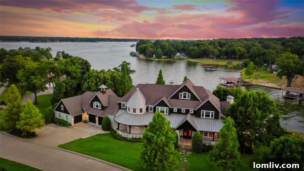 Elegant lakefront mansion with a wrap-around porch and pristine landscaping.