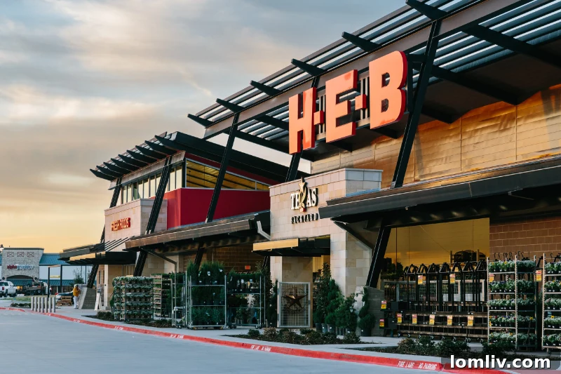 The exterior of a modern H-E-B store in Plano, bustling with shoppers and strategically located near a major intersection.