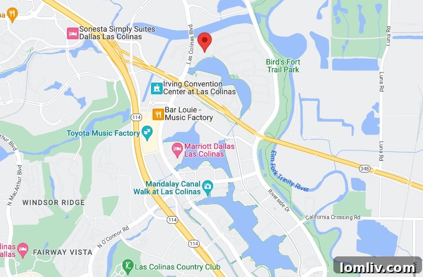 A panoramic view of the Las Colinas business district at sunset, with illuminated buildings and a serene lake.