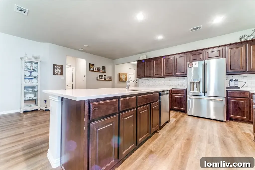 Go West to Springtown: Live the Country Dream on a Budget 7 A modern kitchen with stainless steel appliances, dark wood cabinets, light countertops, and a central island, open to the dining and living areas.