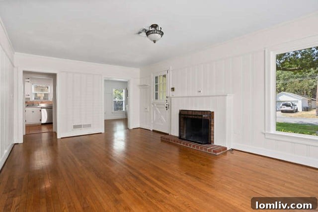 Cozy living room with original hardwood floors and a brick fireplace in a Fort Worth bungalow