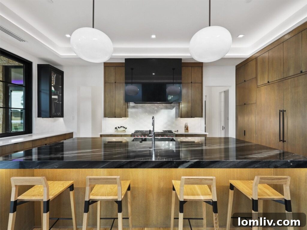 Westlake's Quail Hollow: Redefining Modern Luxury 11 Gourmet kitchen featuring a large island with black marble waterfall countertop and high-end appliances.