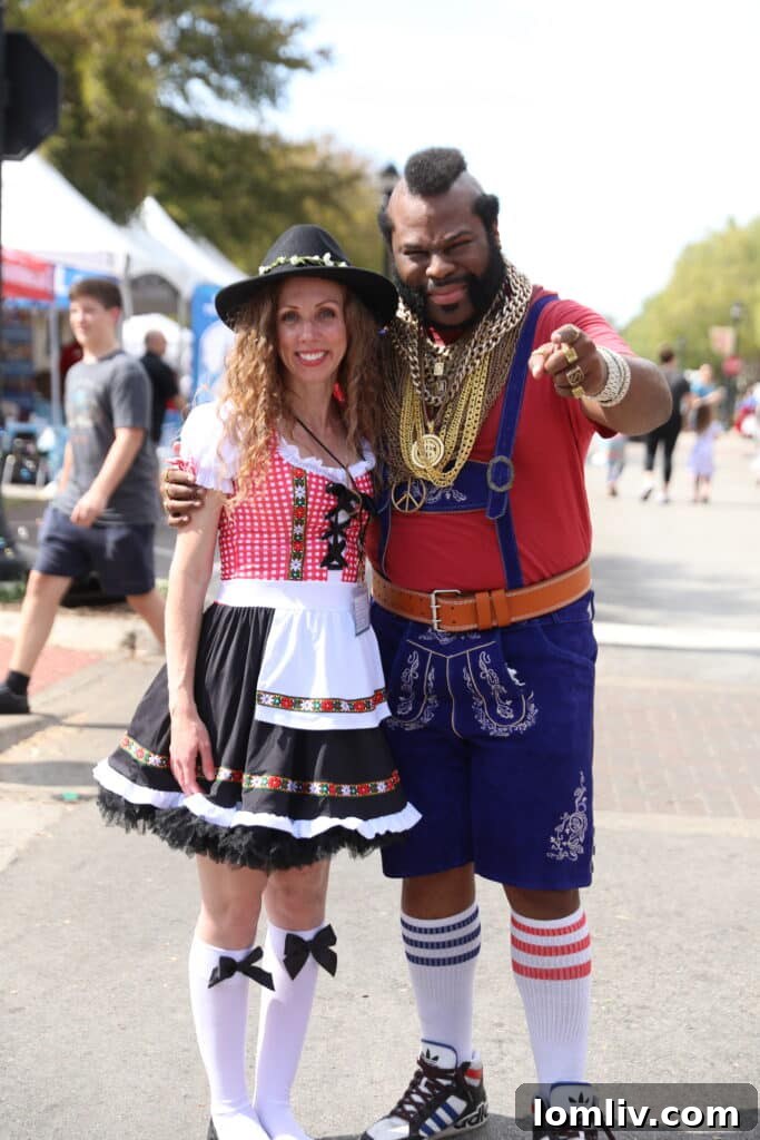A person in traditional lederhosen strolls through Southlake Town Square, with autumn decorations visible.