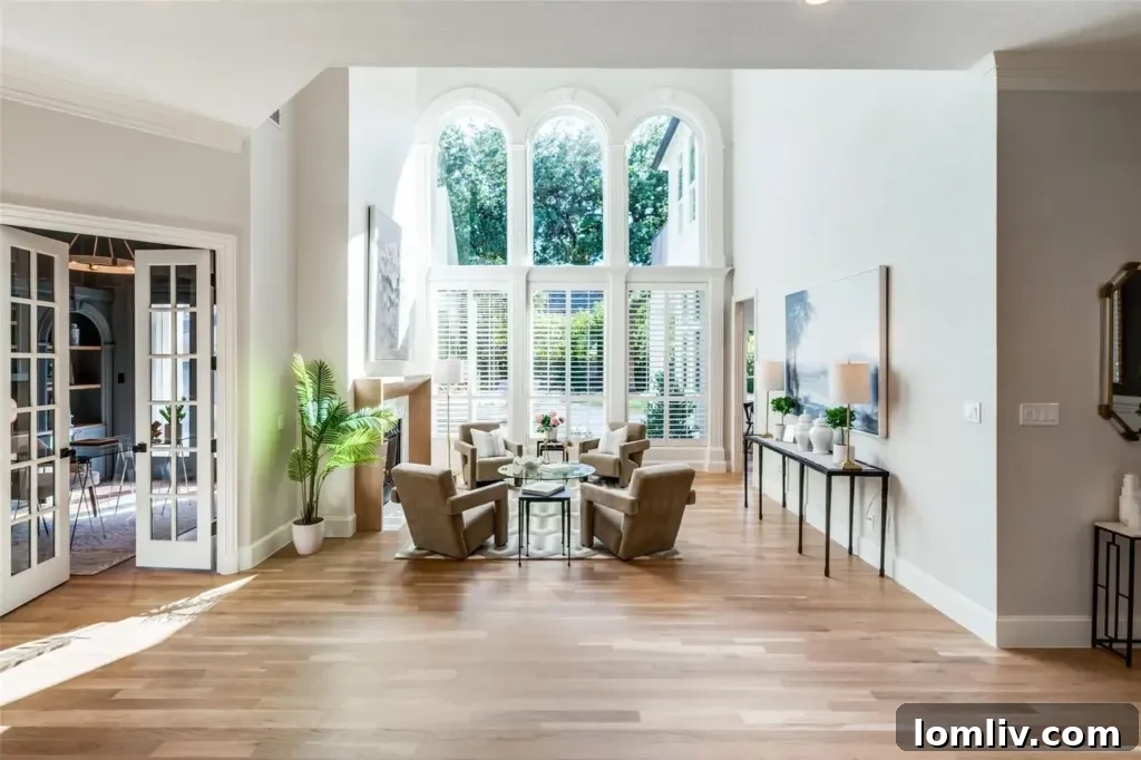 Bright open living room with high ceilings, large windows, and views of the backyard and pool