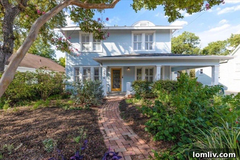 A charming robin's egg blue Craftsman home with golden front doors and a meticulously landscaped front yard, situated on a tree-lined street in the Kings Highway Historic Conservation District, Oak Cliff, Dallas.