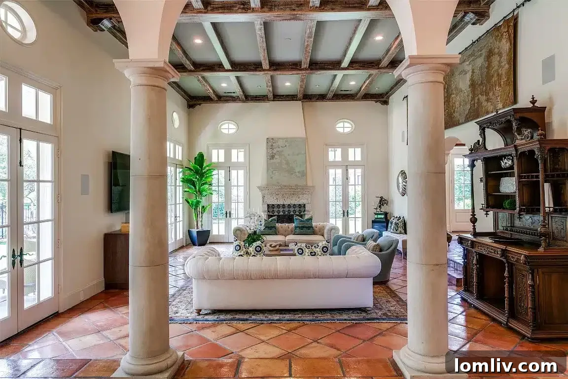 Living area featuring columns, ceiling beams, and Saltillo tile flooring
