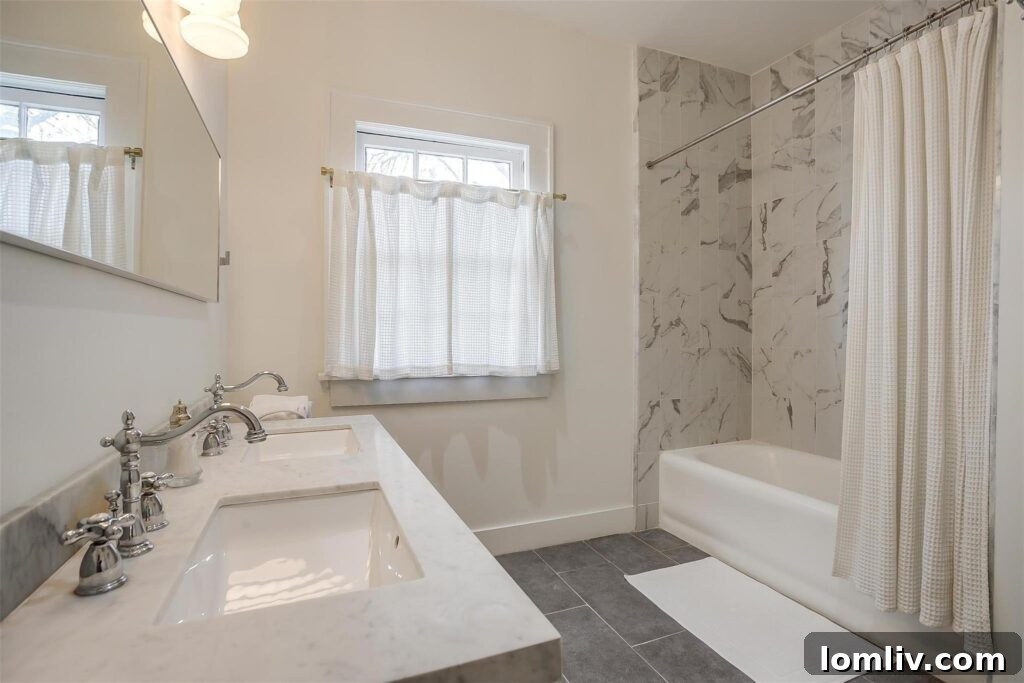 Luxurious renovated bathroom featuring double sinks with marble countertops and floor-to-ceiling porcelain slabs.