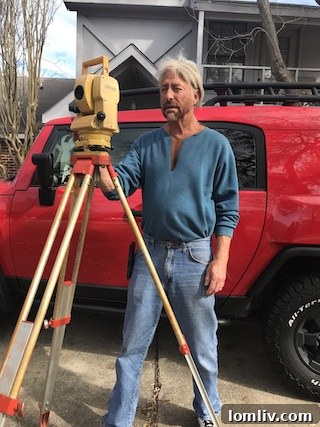Barry Rhodes, an experienced land surveyor, standing outdoors in front of a building, embodying wisdom and dedication in his profession.