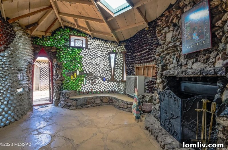 Interior view of the bottle house living area, showing colorful glass bottles embedded in the walls, creating a vibrant, light-filled atmosphere.