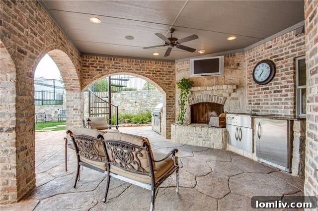 Elegant outdoor living area with a fireplace and kitchen, offering golf course views