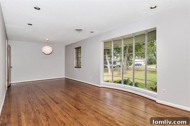 Spacious living area with large bay window and hardwood floors