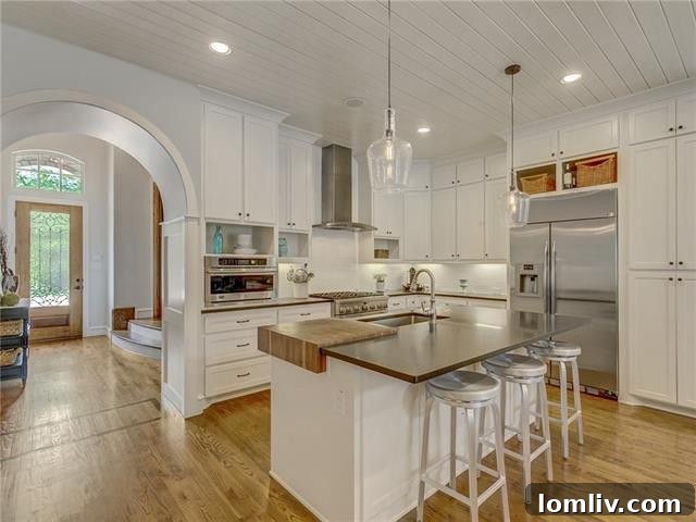 Bright and airy modern farmhouse kitchen with an elegant arched entryway, white cabinetry, and a large island.