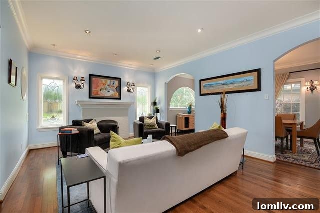 Elegant formal dining room with arched doorway, hardwood floors, and ample natural light
