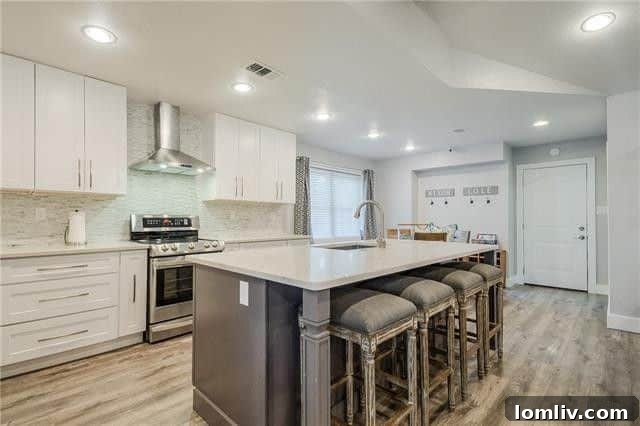 Modern kitchen with soft-close white Shaker cabinets, quartz island, and stainless steel appliances