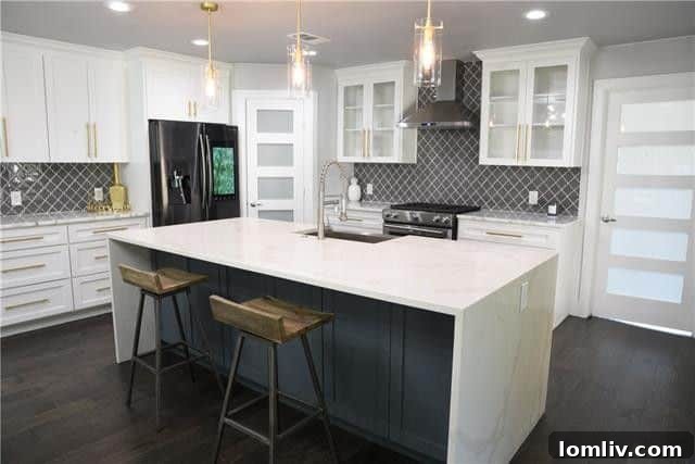 Modern kitchen with white custom cabinets, granite counters, and a quartz island with waterfall edges