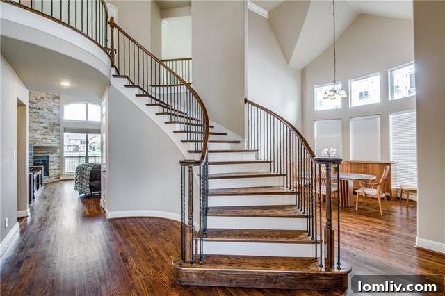Grand foyer with a sweeping staircase and an abundance of natural light, showcasing the home's open floor plan.