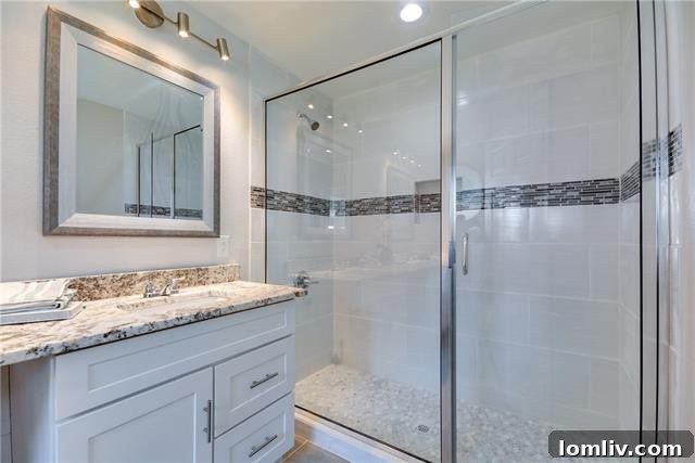 A second renovated bathroom with mosaic accents and neutral tones, offering a spa-like retreat.