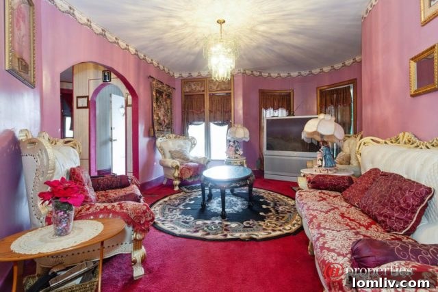 Ornate pink living room with abundant furniture, velvet textures, and decorative elements