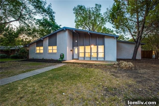Exterior view of a welcoming Midcentury Ranch home in North Dallas, showing a well-maintained facade and a glimpse of the surrounding greenery.