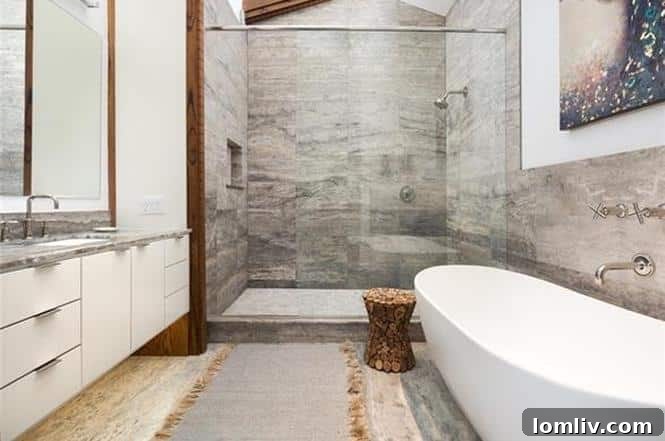 Elegant master bathroom featuring a standalone shower with silver vein-cut travertine and deep vessel tub