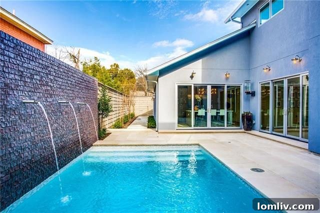 Spacious open-concept living room with smooth stone fireplace, wide plank wood floors, and a beautiful view of the backyard pool