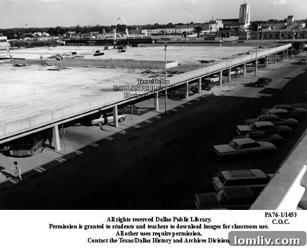 Detailed aerial view of the Preston Center parking garage, showing its aged structure amidst modern buildings.