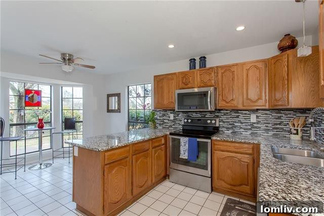 Contemporary updated kitchen with granite countertops, tile backsplash, and stainless steel appliances