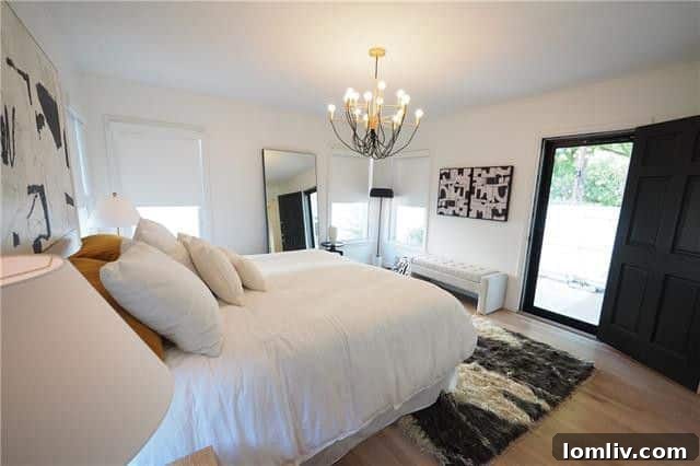 Bright bedroom with vaulted ceiling and large windows overlooking a backyard