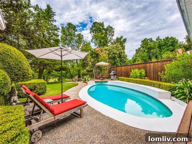 Private backyard oasis with a sparkling blue swimming pool, expansive patio, and mature trees in a Farmers Branch family home.
