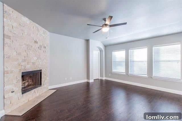 A cozy living room with a stacked stone fireplace, modern ceiling fan, and comfortable seating in a Rockwall home.