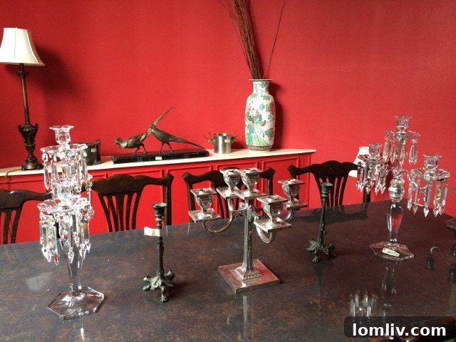 Elegant rounded dining room in Unit 2B, featuring rich red walls, a banquet-sized mahogany dining table, a candelabra, and a bronze sculpture in the background