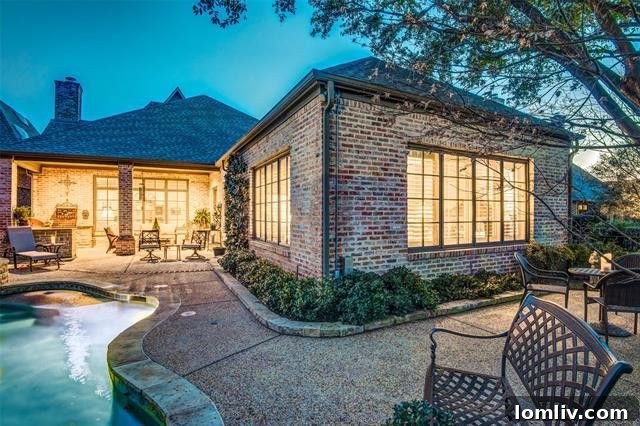 Stunning backyard oasis featuring a heated pool, covered patio, outdoor kitchen, and tranquil greenbelt views.