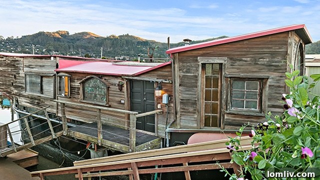 The exterior of Shel Silverstein's historic Sausalito houseboat, a converted WWII balloon barge, with unique architectural details and waterfront views in the picturesque Bay Area.