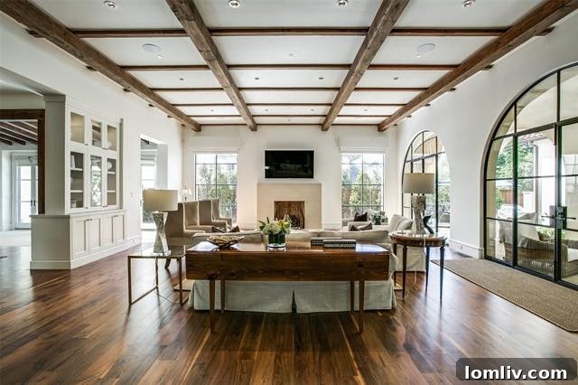 The great room with a limestone fireplace, cross-beamed ceiling, and Palladian French doors