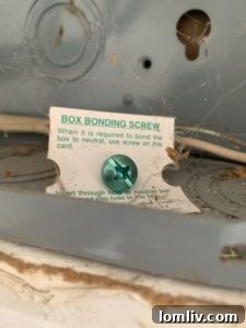 Close-up of an uninstalled green bonding screw resting inside an electrical panel box.