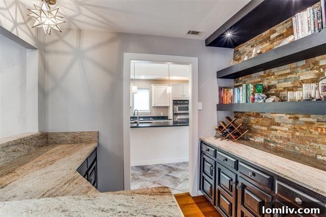 Far North Dallas Digs Where Every Angle Clicks 7 Spacious kitchen with white cabinets, stainless appliances, and black granite counters