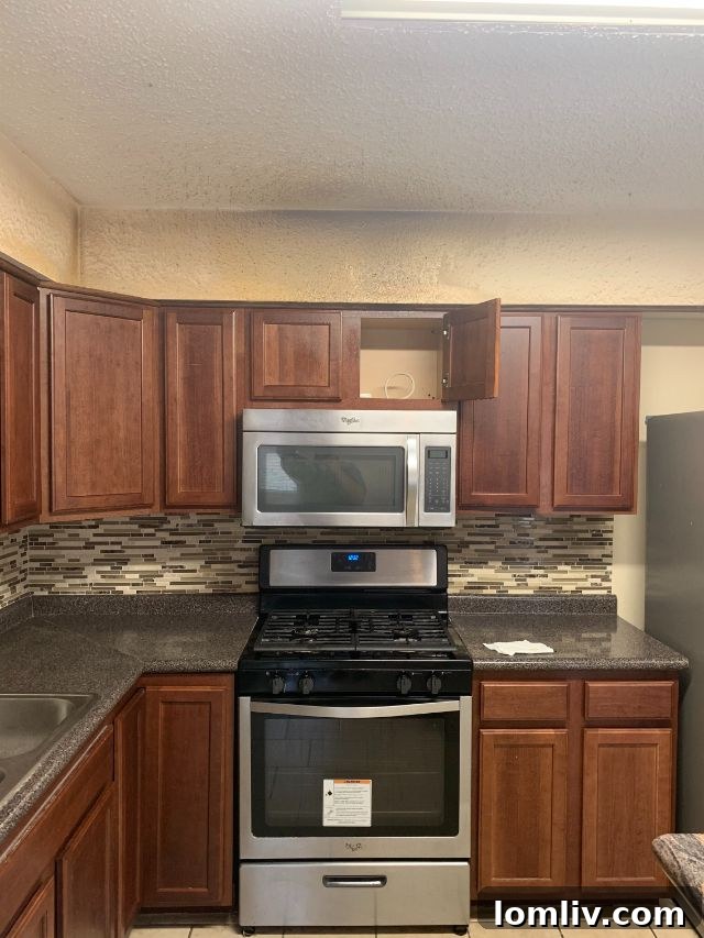 Gas stove in a kitchen without an exhaust vent, showing accumulated grease and grime on the adjacent wall surface.